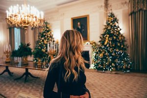 Woman with wavy blonde hair standing in front of a Christmas tree